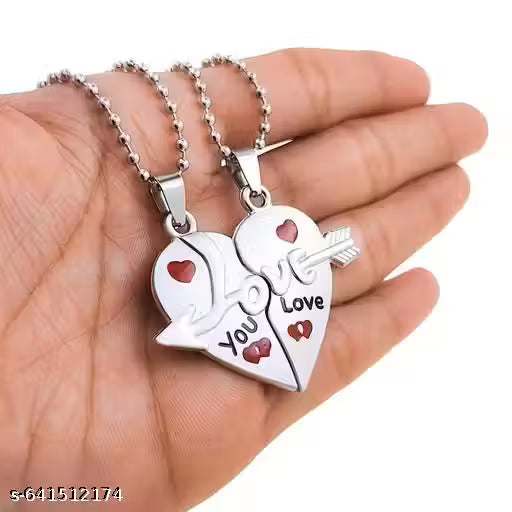 Two heart-shaped silver pendants with 'You Love' engraving held in a hand.